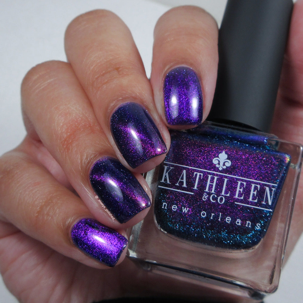 Purple cat-eye glittery nail polish with a bottle labeled &