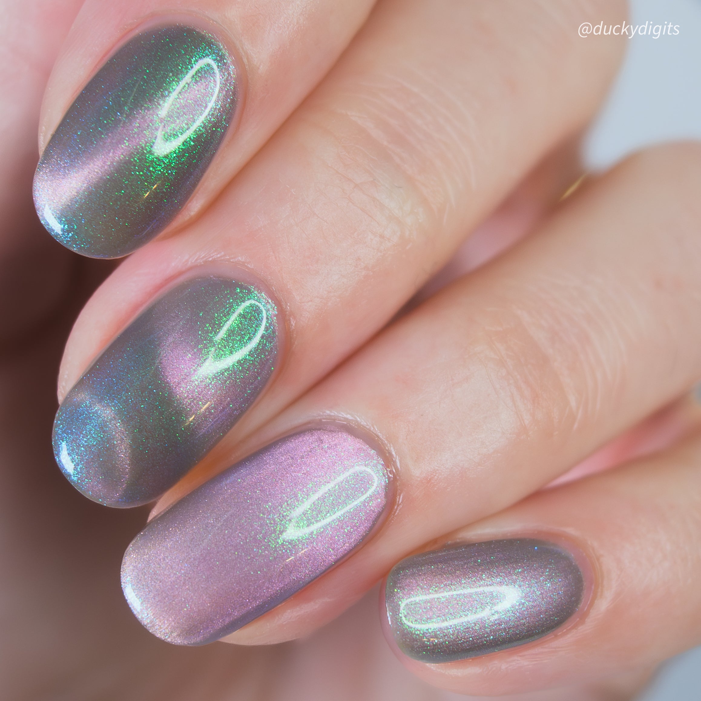 Close-up of a hand with magnetic pink and green nail polish.