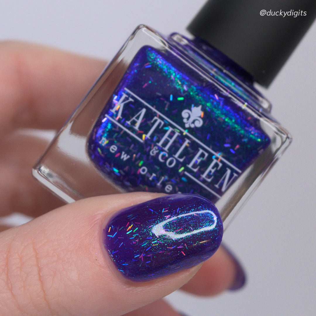 Nail polish bottle with colorful glittery nail polish on a finger, brand &