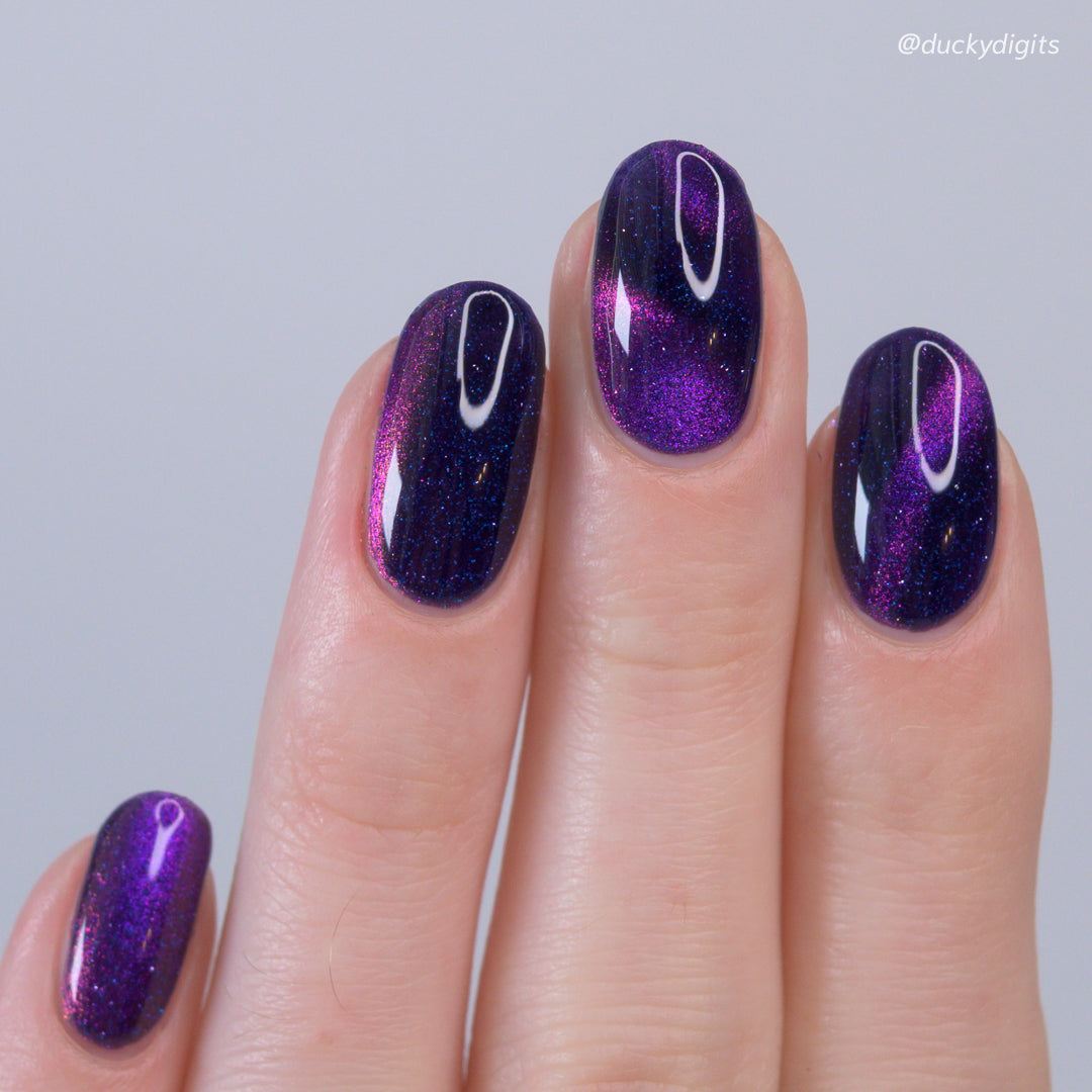 Nail polish with purple and pink cat eye magnetic on a neutral background