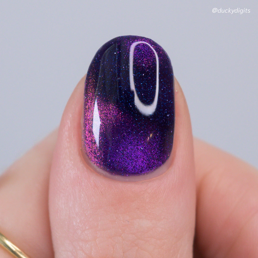 Galaxy Nail with purple magnetic and reflecitve glitter polish on a neutral background
