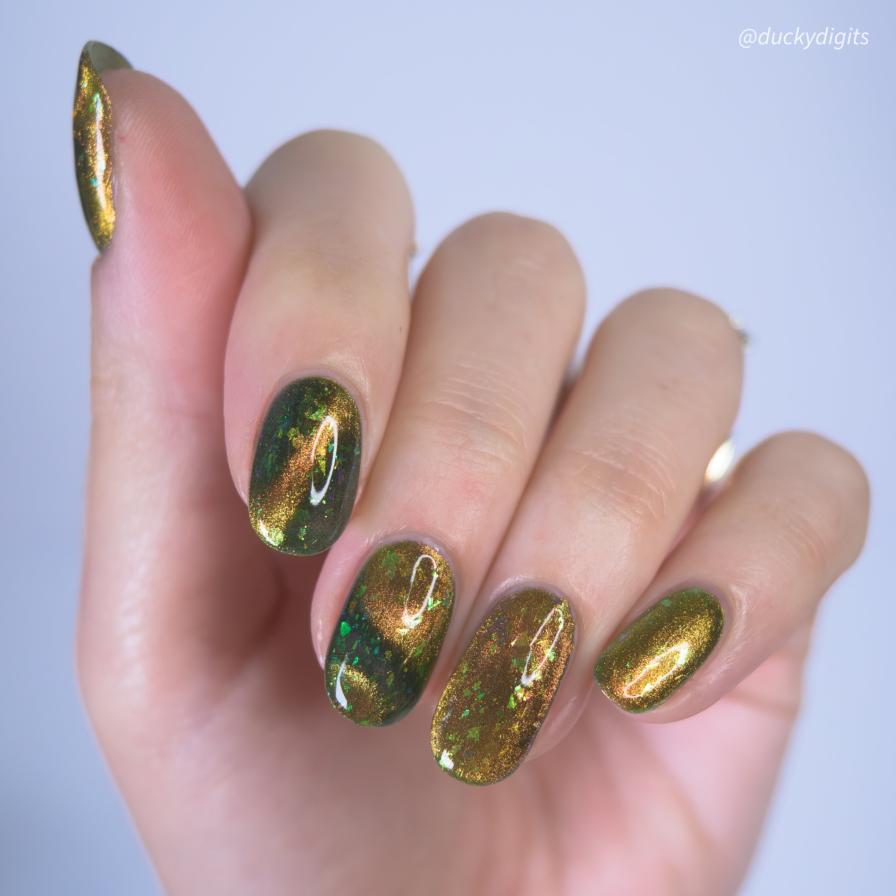 Hand with green and gold magnetic nail polish on a white background