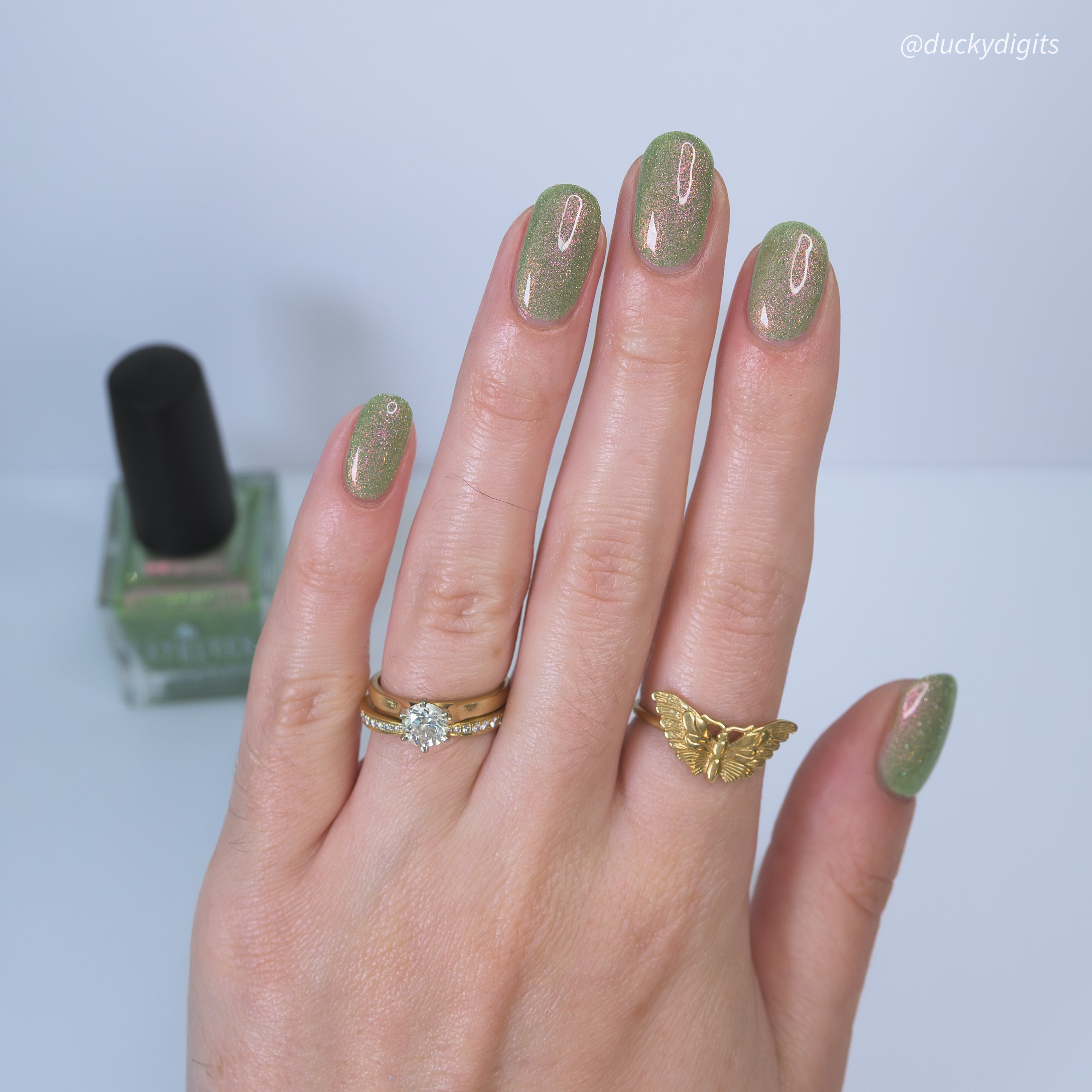 Green reflective glitter nail polish with a visible brand name on the bottle.