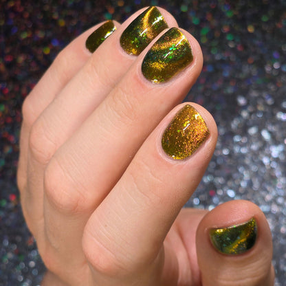 Hand with gold and green magnetic nail polish against a glittery background