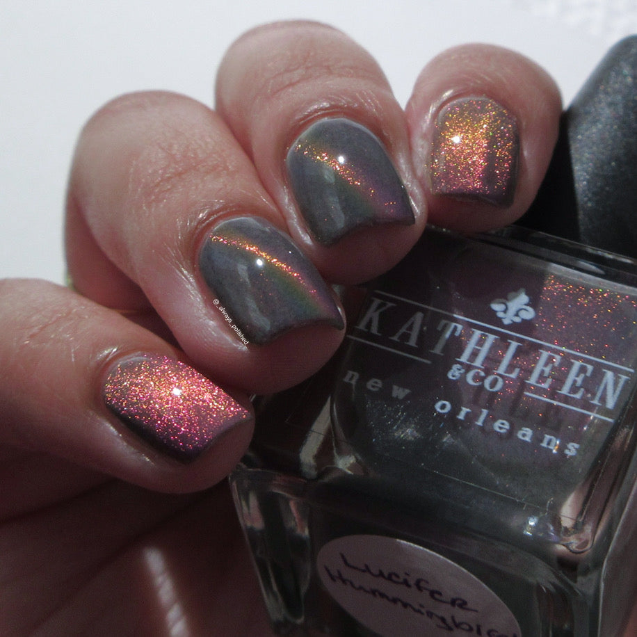Nails with magnetic polish held next to a bottle of Kathleen &amp; Co. nail polish.