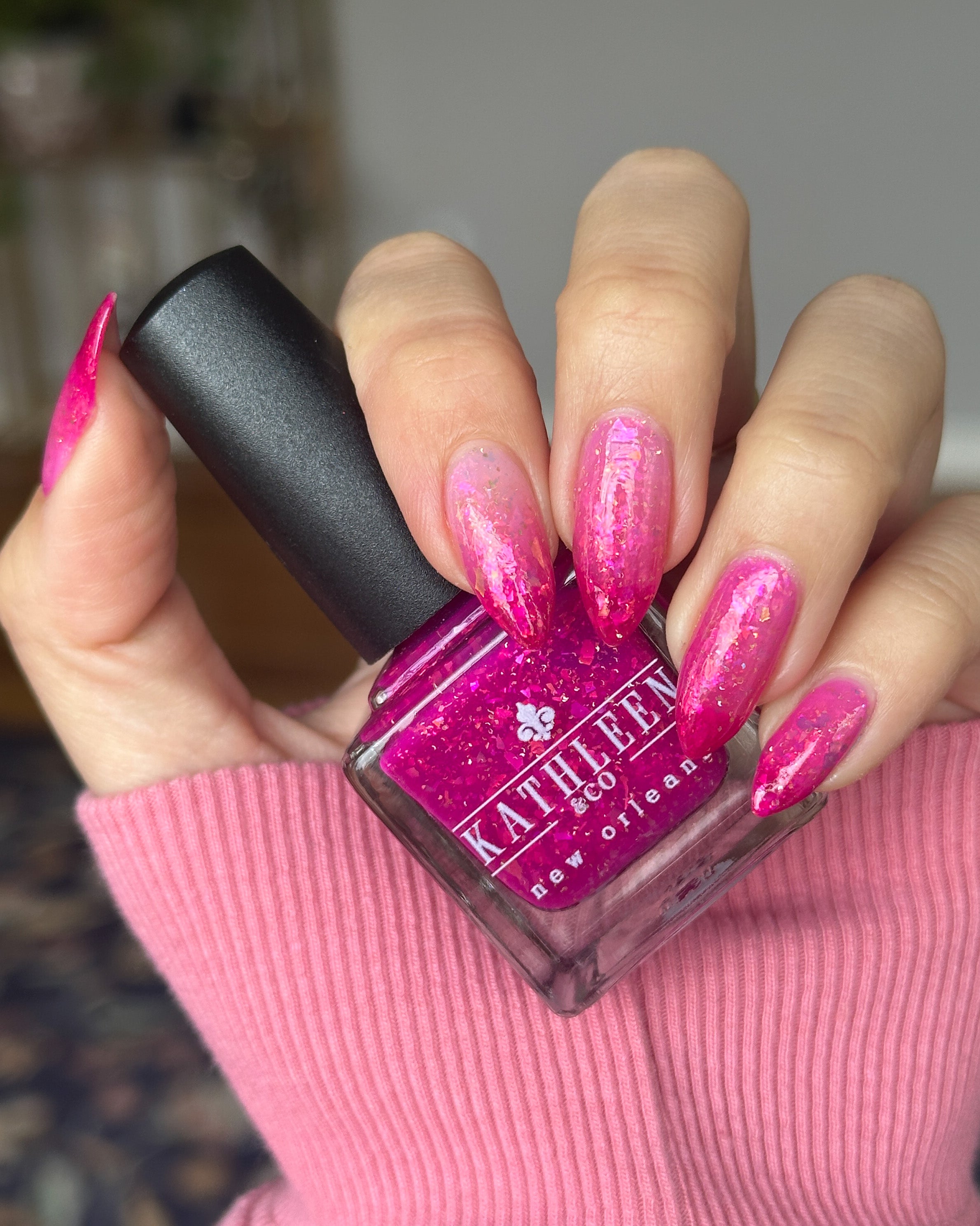 Hand with pink thermal nails holding a bottle of pink nail polish