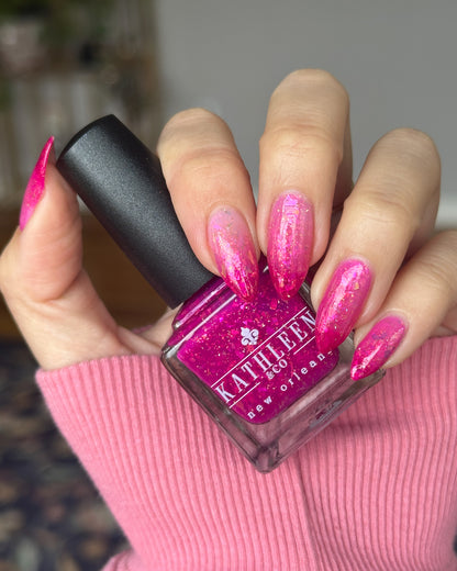 Hand with pink thermal nails holding a bottle of pink nail polish