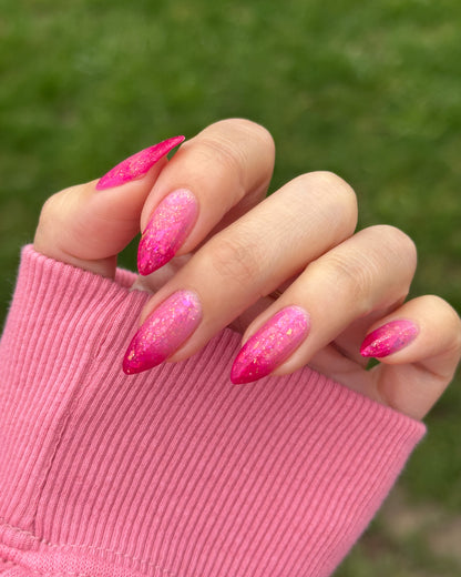 Hand with pink thermal nails wearing a pink sleeve against a green background