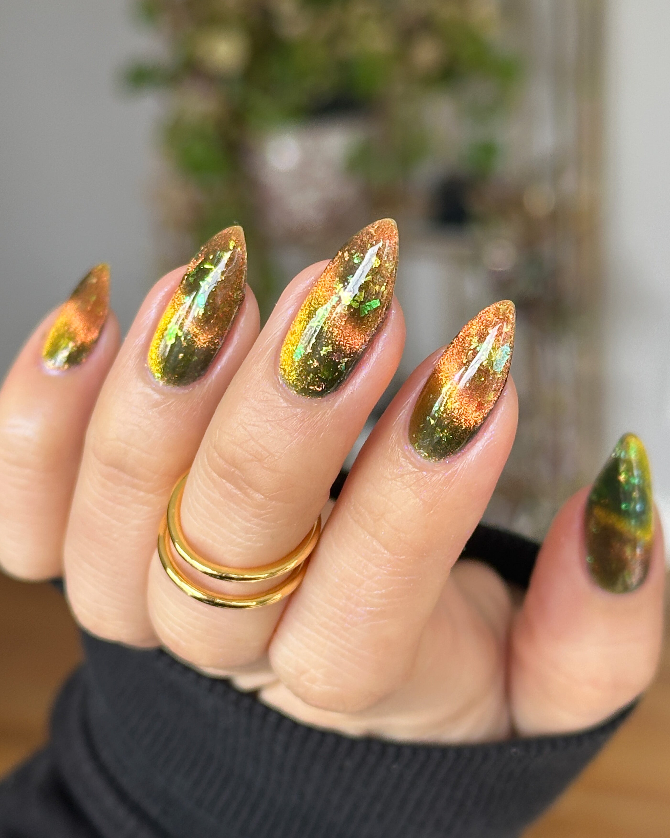 Nail art with a magnetic  gold and green design on a blurred background