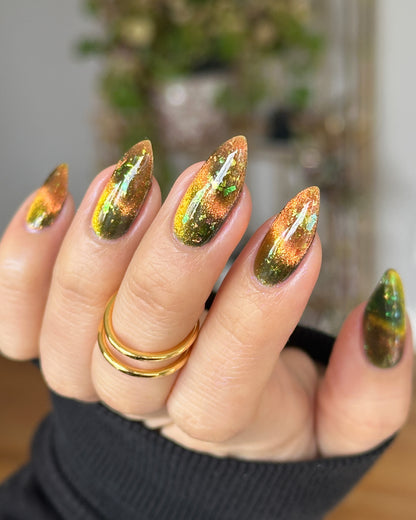 Nail art with a magnetic  gold and green design on a blurred background