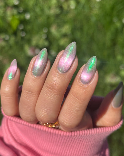Nails  with pink and green magnetic nail polish on a blurred green background