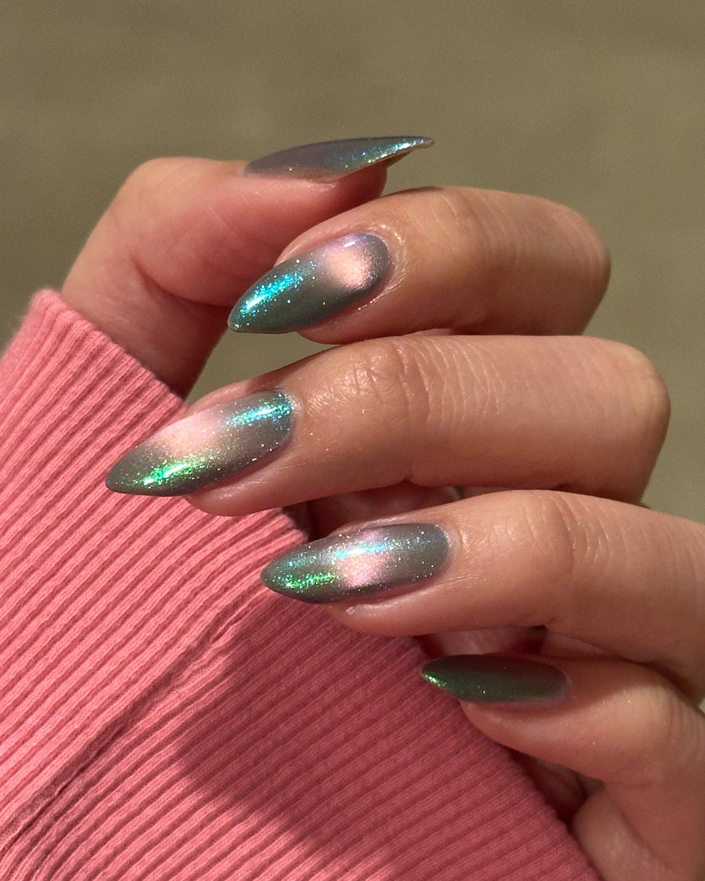 Close-up of a hand with magnetic nail polish on a pink sleeve.