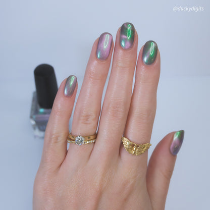 Hand with gold rings and magnetic nail polish on a light background