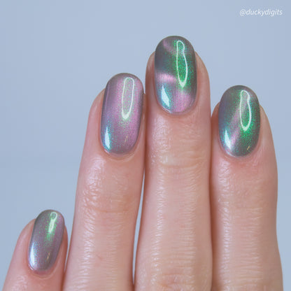 Nails with metallic green and pink polish on a neutral background
