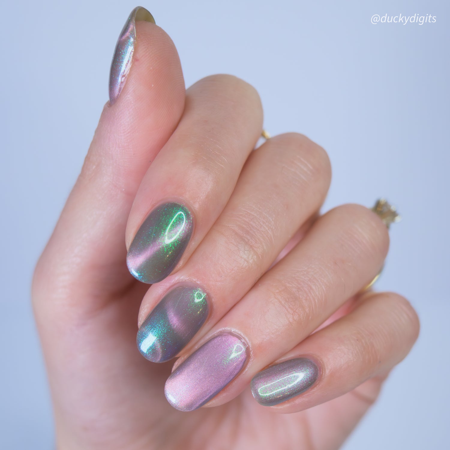 Hand with iridescent nail polish on a light background