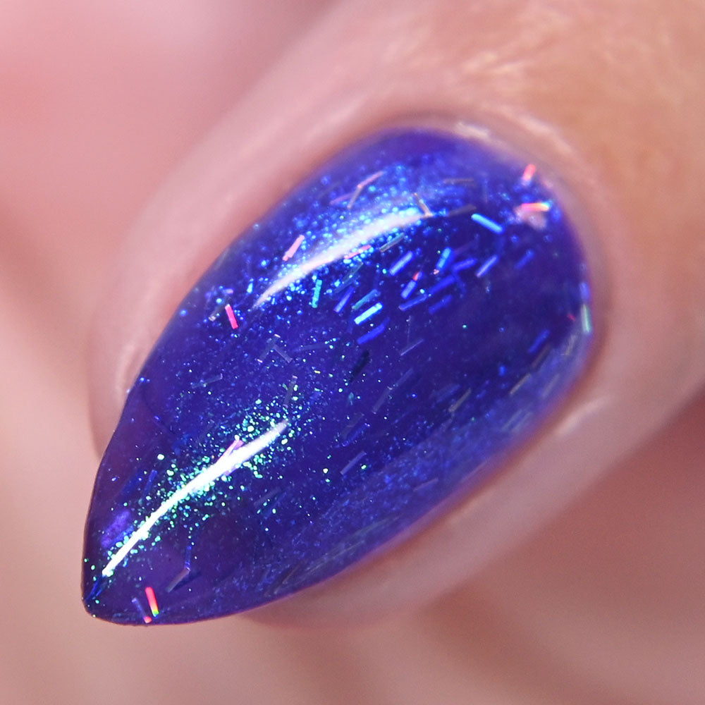Nail with purple glittery nail polish on a blurred background