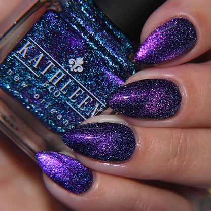 Close-up of a hand with purple glittery nail polish holding a bottle of Kathleen &amp; Co new orleans nail polish.