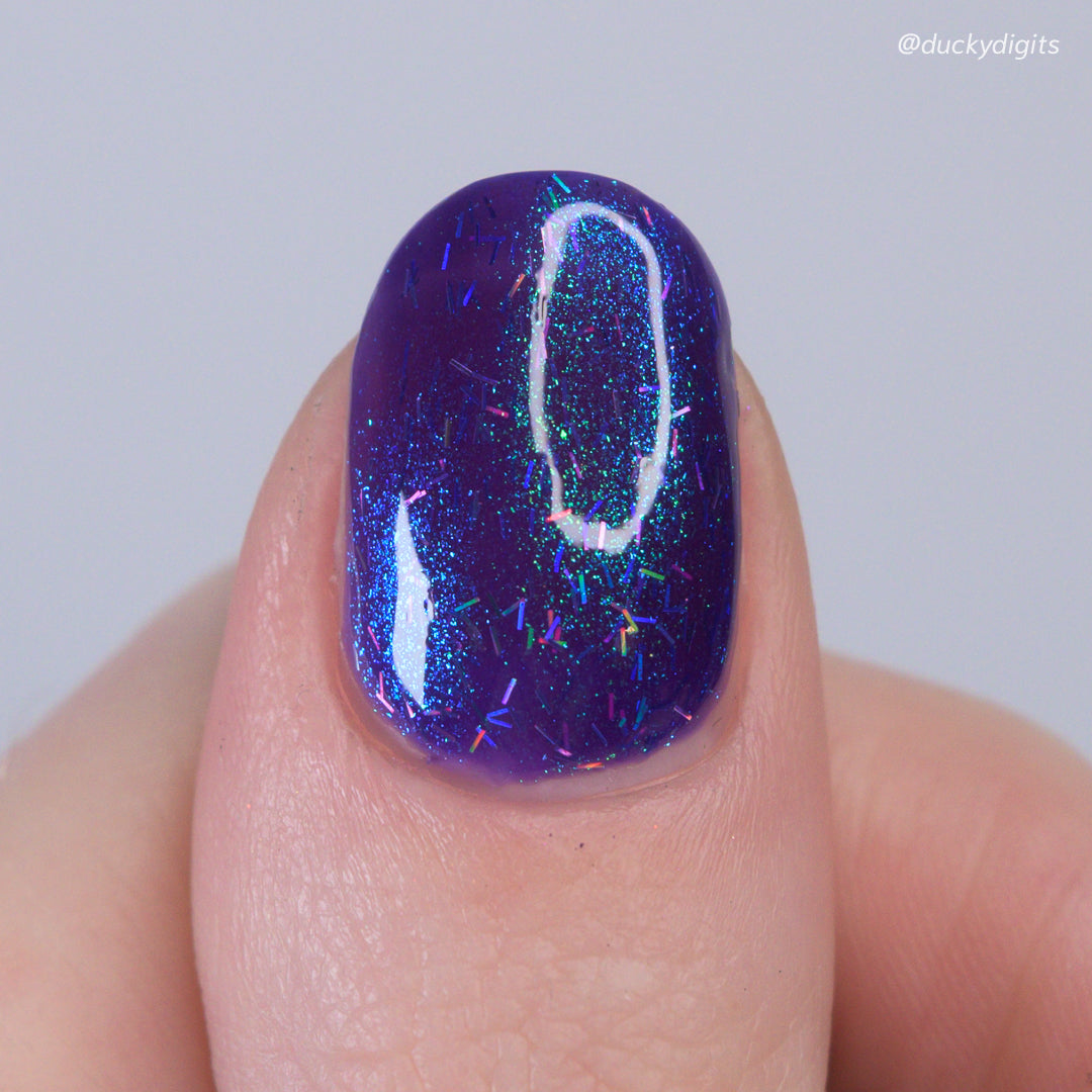 Nail with purple glittery nail polish on a neutral background