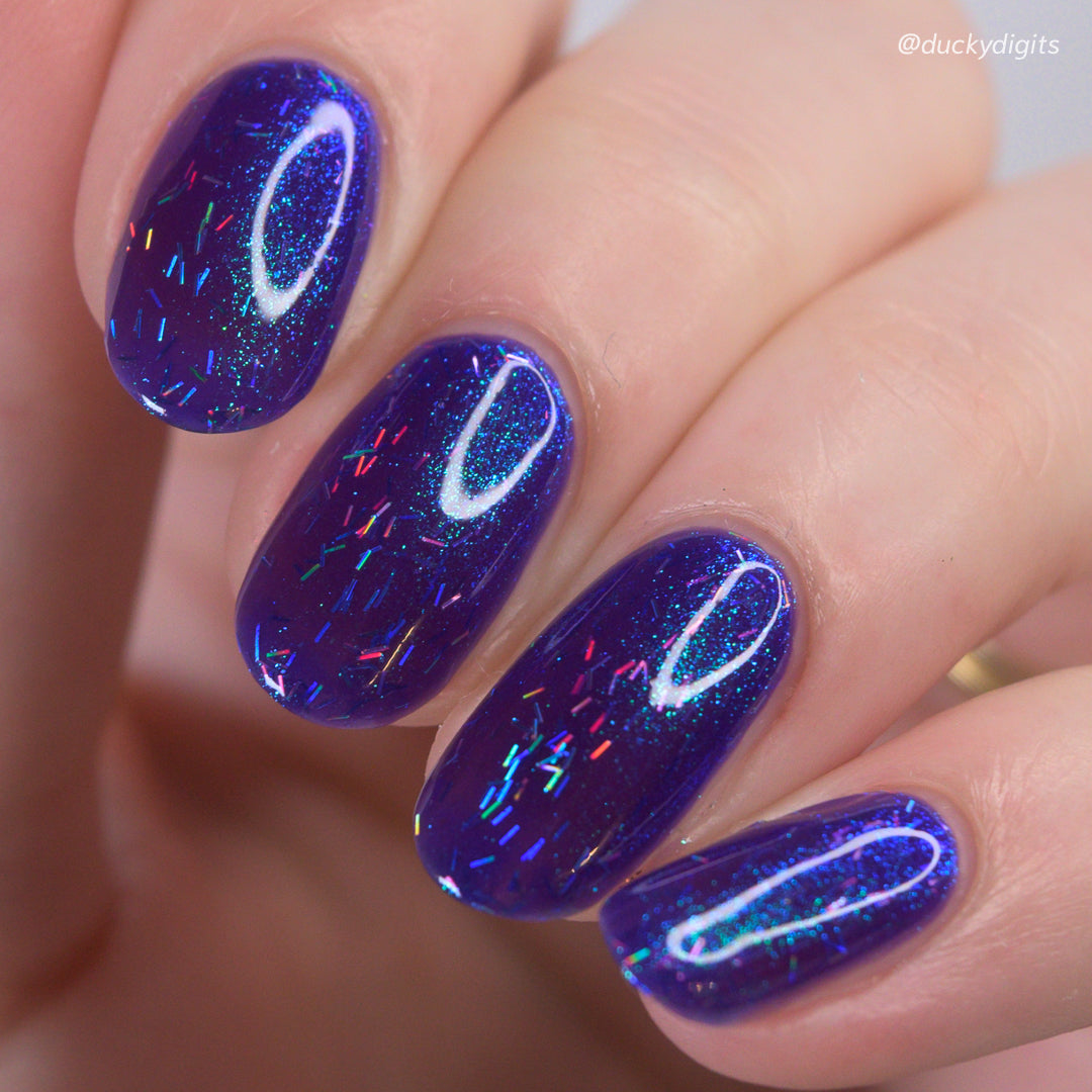Close-up of a hand with purple glittery nail polish on a blurred background