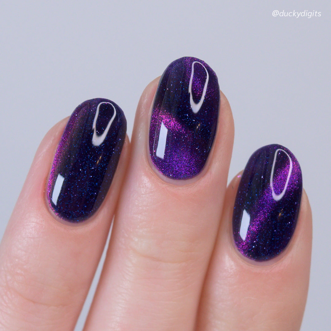 Nails with purple glitter design on a light gray background