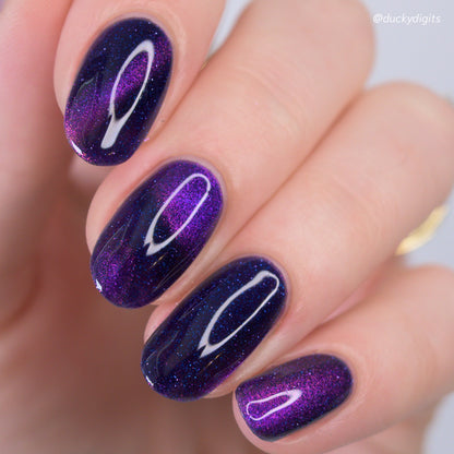 Nails with purple magnetic glitter design on a neutral background