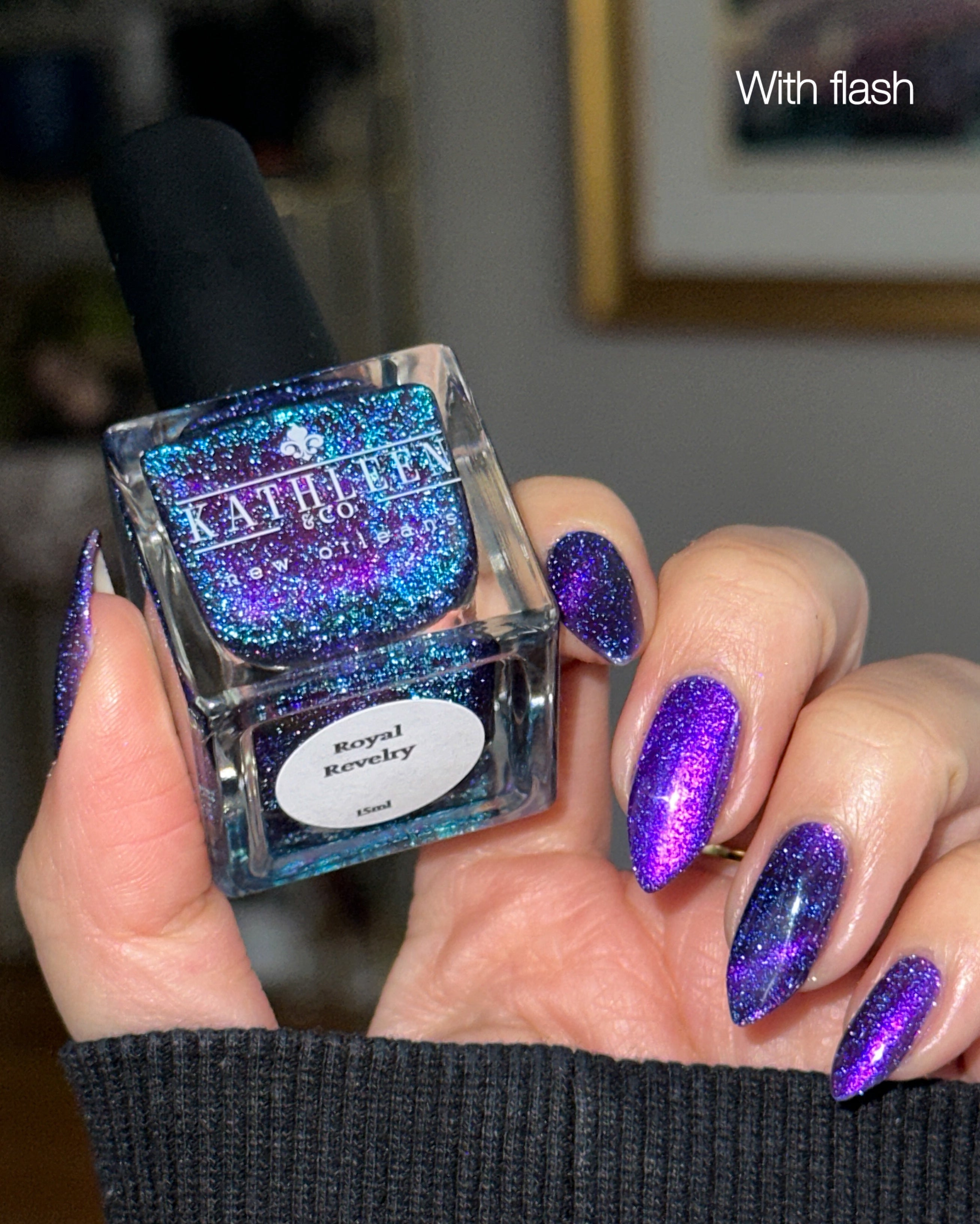 Nail polish bottle with glittery blue and purple nails, labeled &