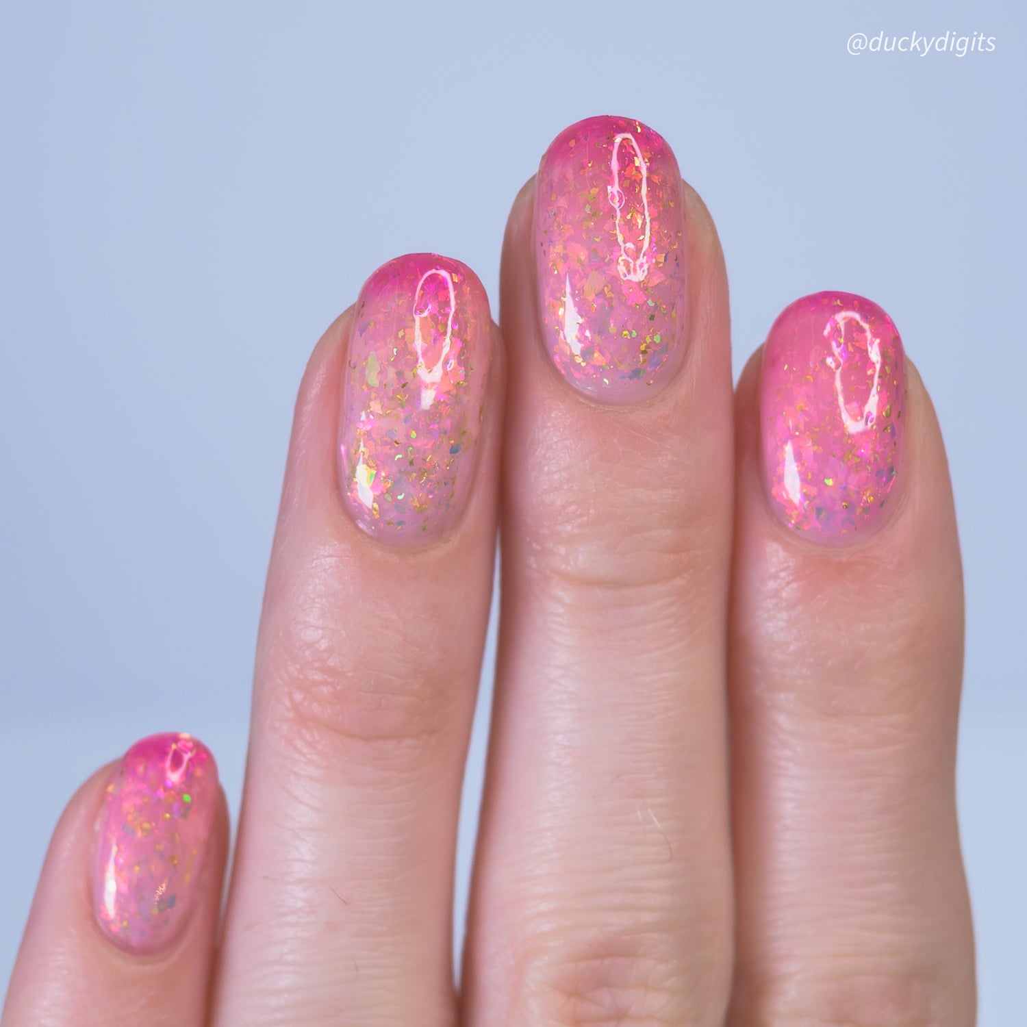 Hand with pink thermal nail polish on a light blue background