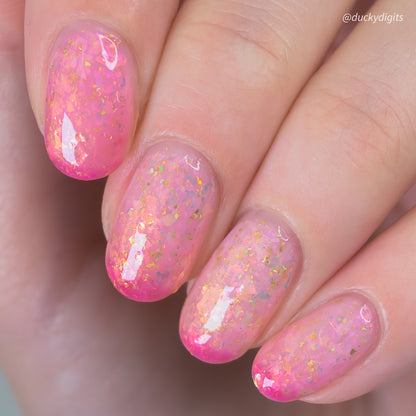 Close-up of a hand with pink thermal nail polish on a neutral background
