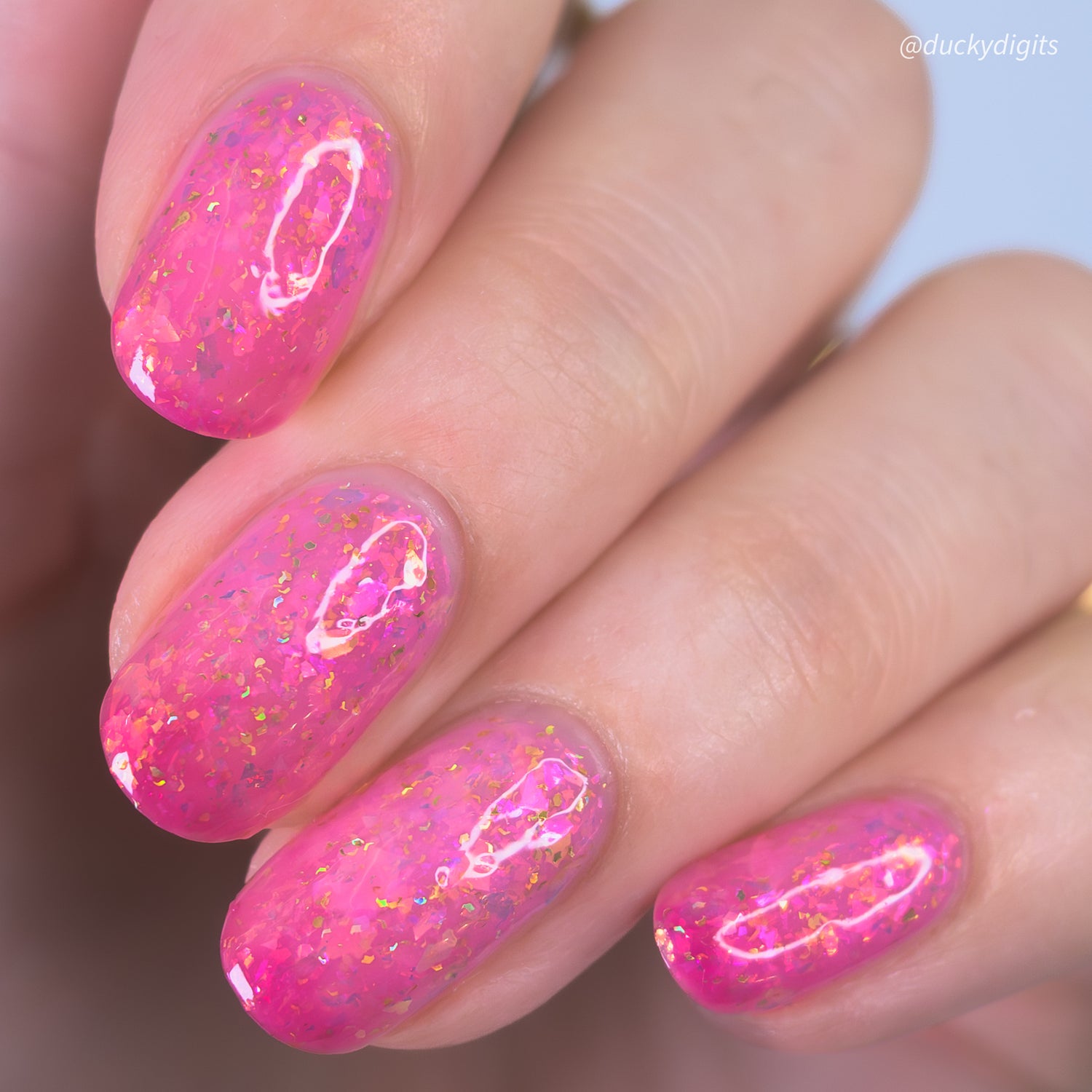 Close-up of a hand with pink thermal nail polish on a blurred background