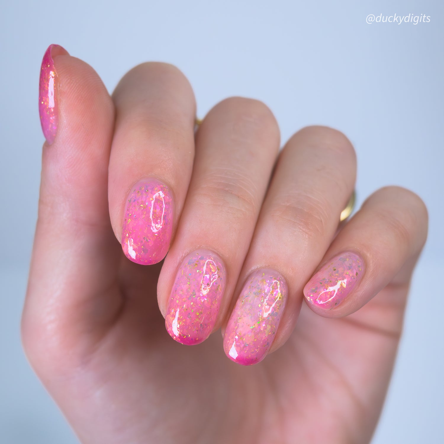 Hand with pink thermal nail polish on a light background
