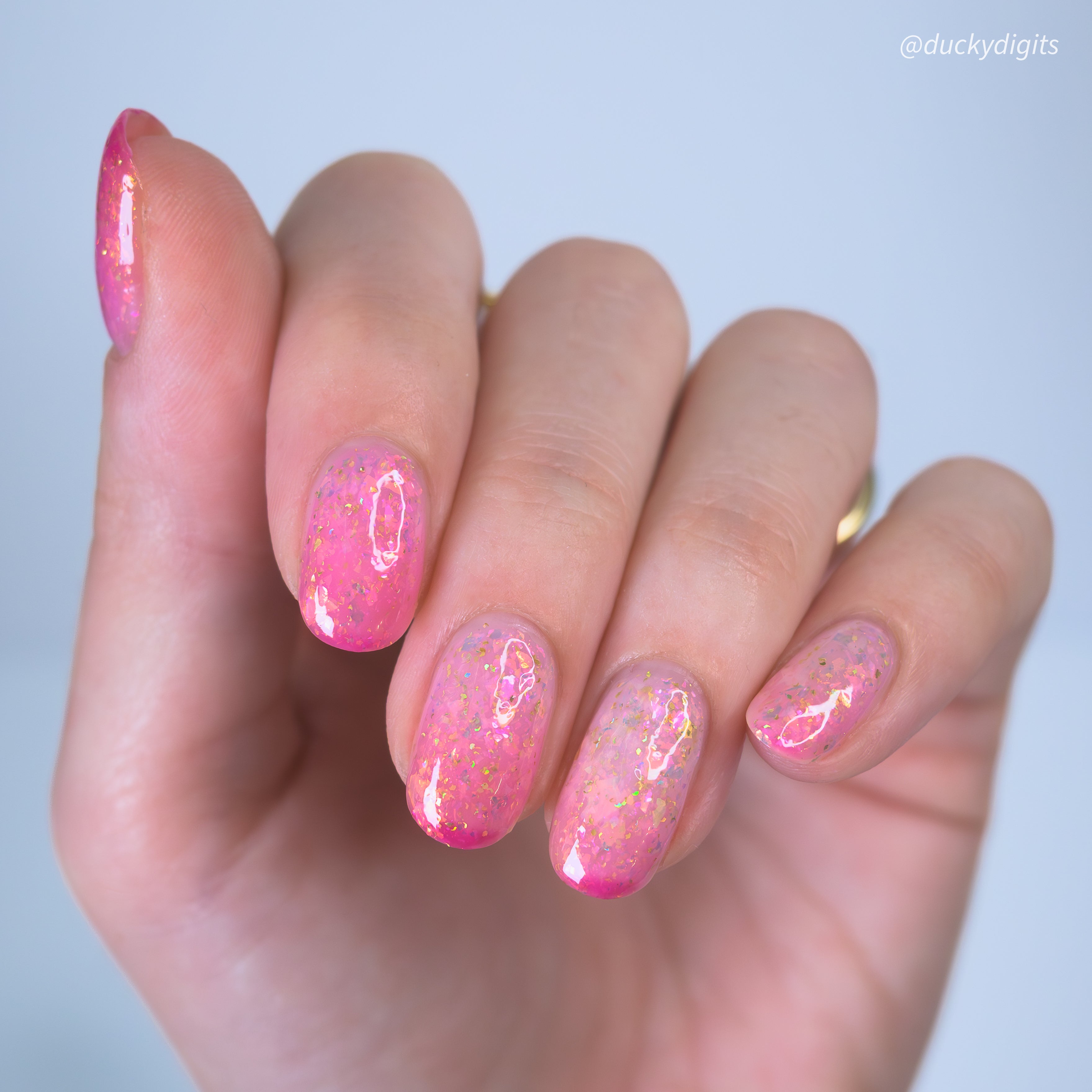 Hand with pink thermal nail polish on a light background