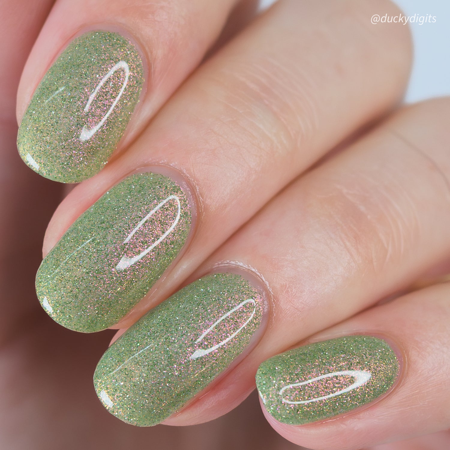 Green reflective glitter nail polish on nails