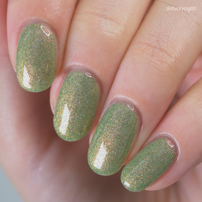 Close-up of a hand with green reflective glittery nail polish.