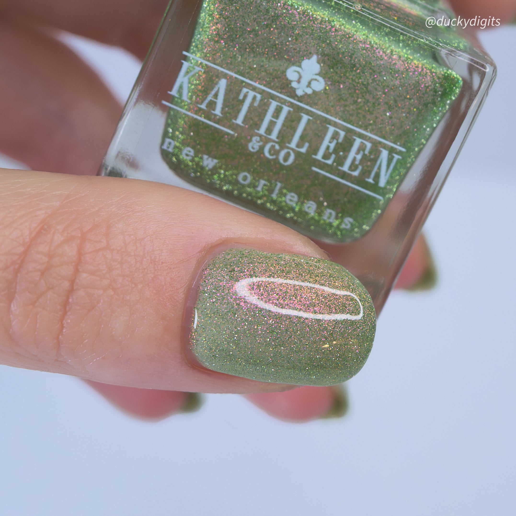 Green reflective glittery nail polish with a "Kathleen &amp; Co." polish bottle.