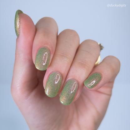 Hand with greenreflective glitter nail polish on a light gray background