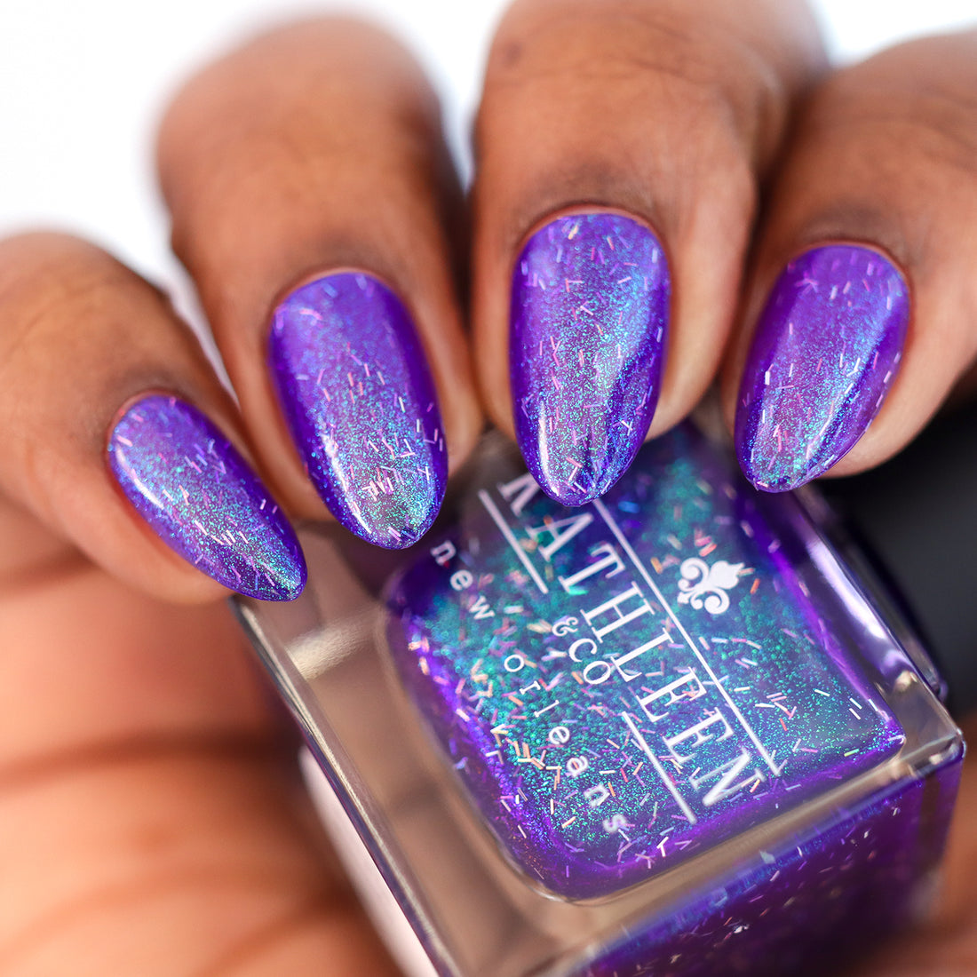 Kathleen &amp; Co Purple glittery nail polish with a bottle of the same polish held by a hand.
