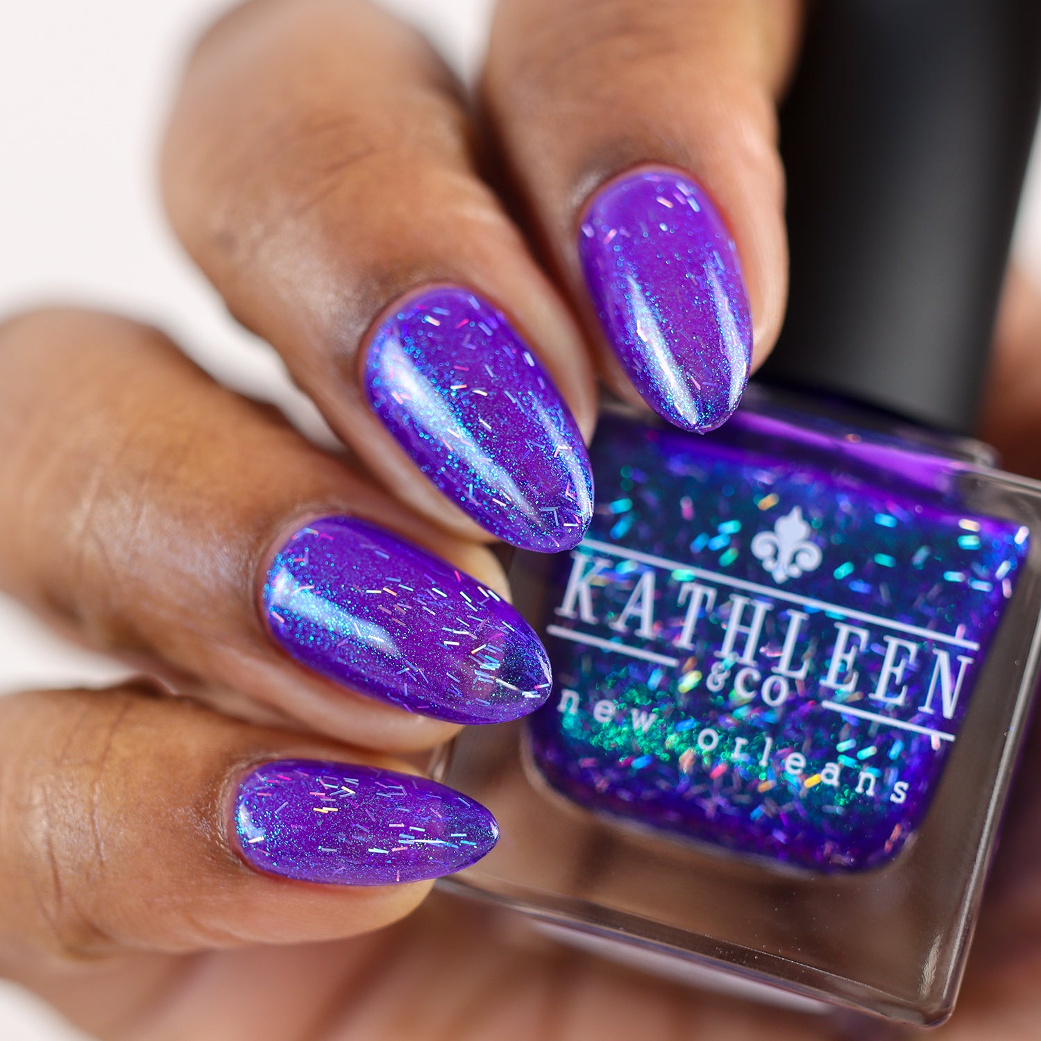 Purple glittery nail polish with a bottle labeled &