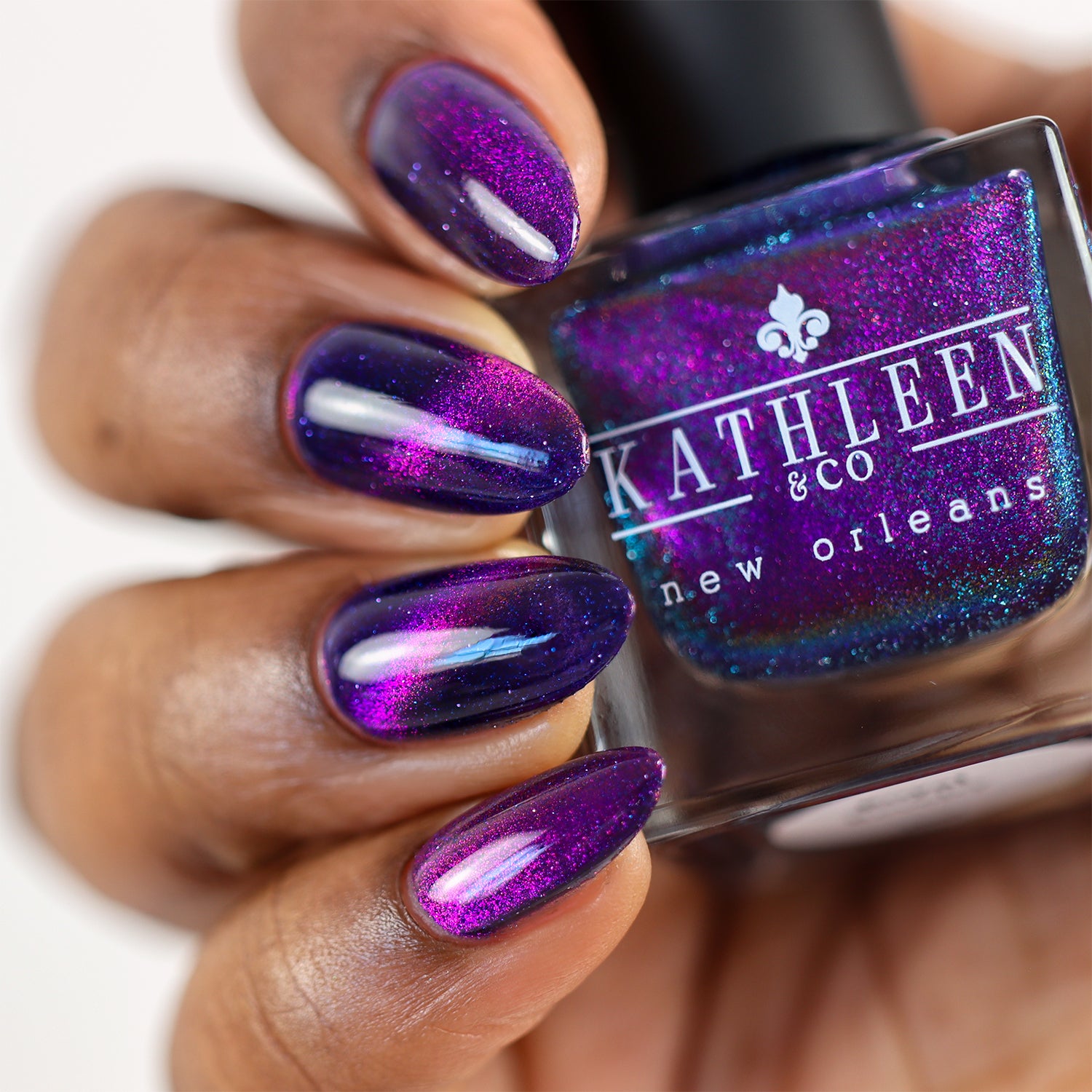 Purple magentic glitter nail polish on nails with a bottle of Kathleen &amp; Co New Orleans nail polish.